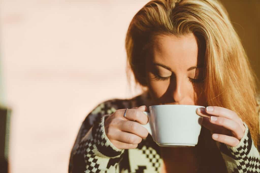 blonde woman sipping on a coffee mug