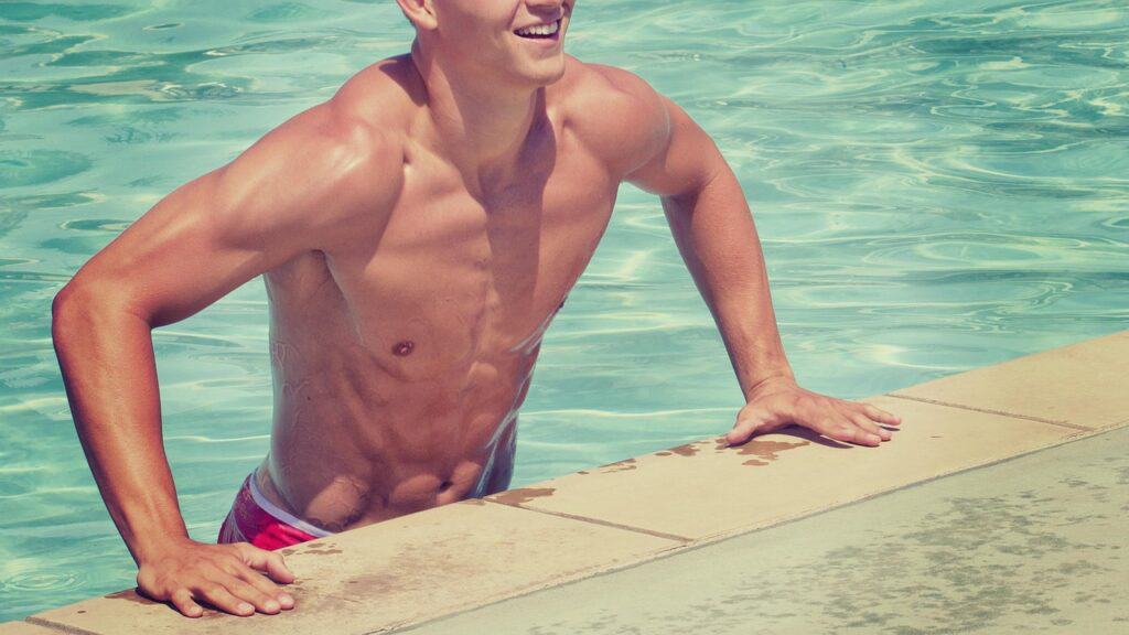 shirtless man coming out of a pool