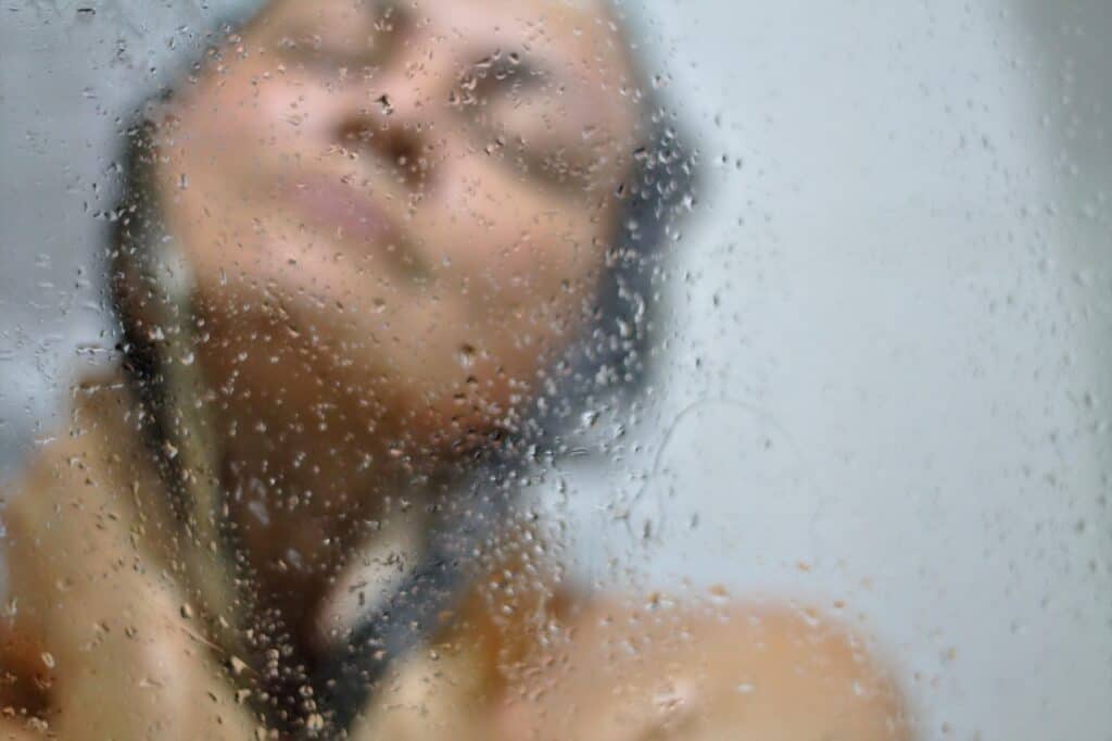 woman showering and a wet water glass